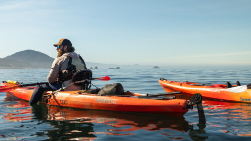 A man and woman in kayaks on an open body of water.