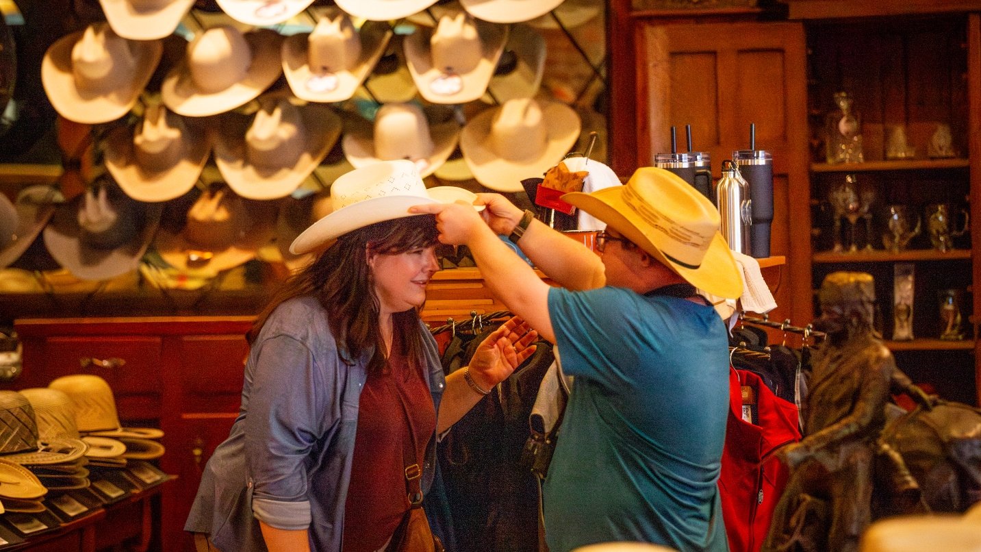 Man and woman try on cowboy hats in store
