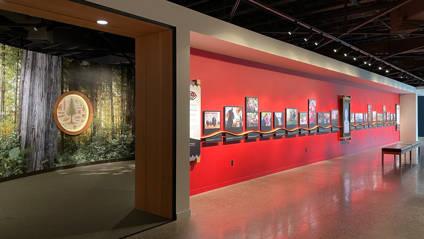 A photo exhibit along a red wall.