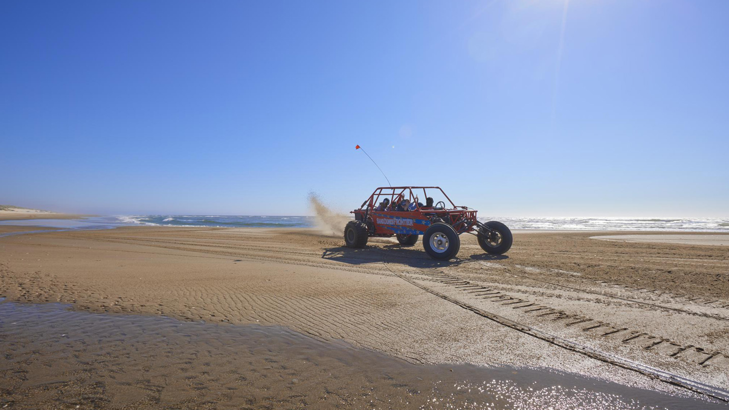 A dune buggy riding across a sand dune.