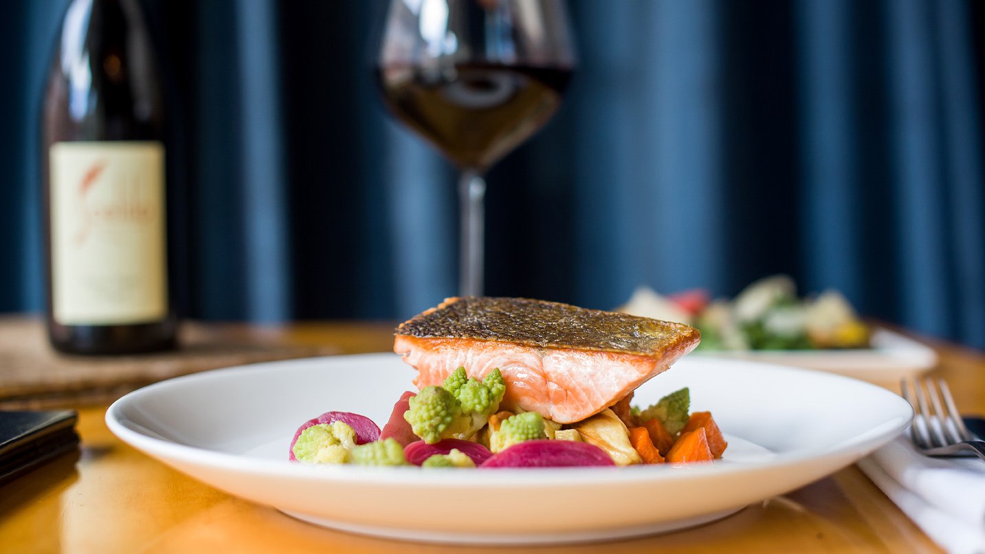 A salmon dish over vegetables.