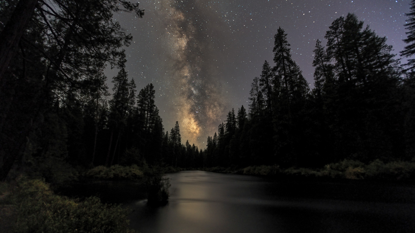 A dark starry night above a river.