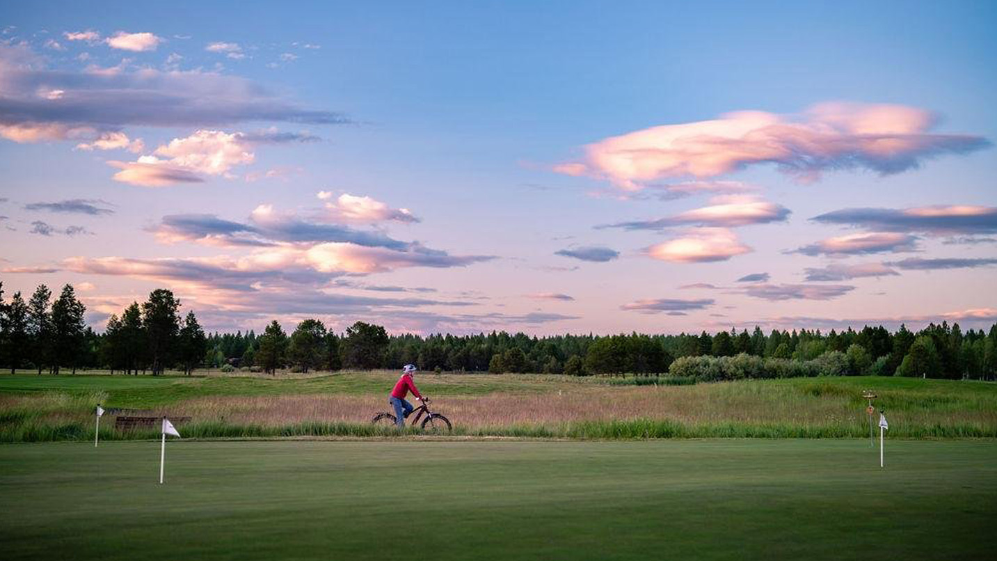 A cyclist riding a path through a golf course.