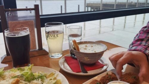 Table of food and beverages next to a waterfront view