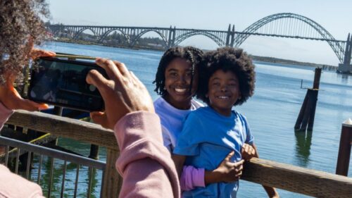 Boy and girl smile at camera with bay and bridge in background