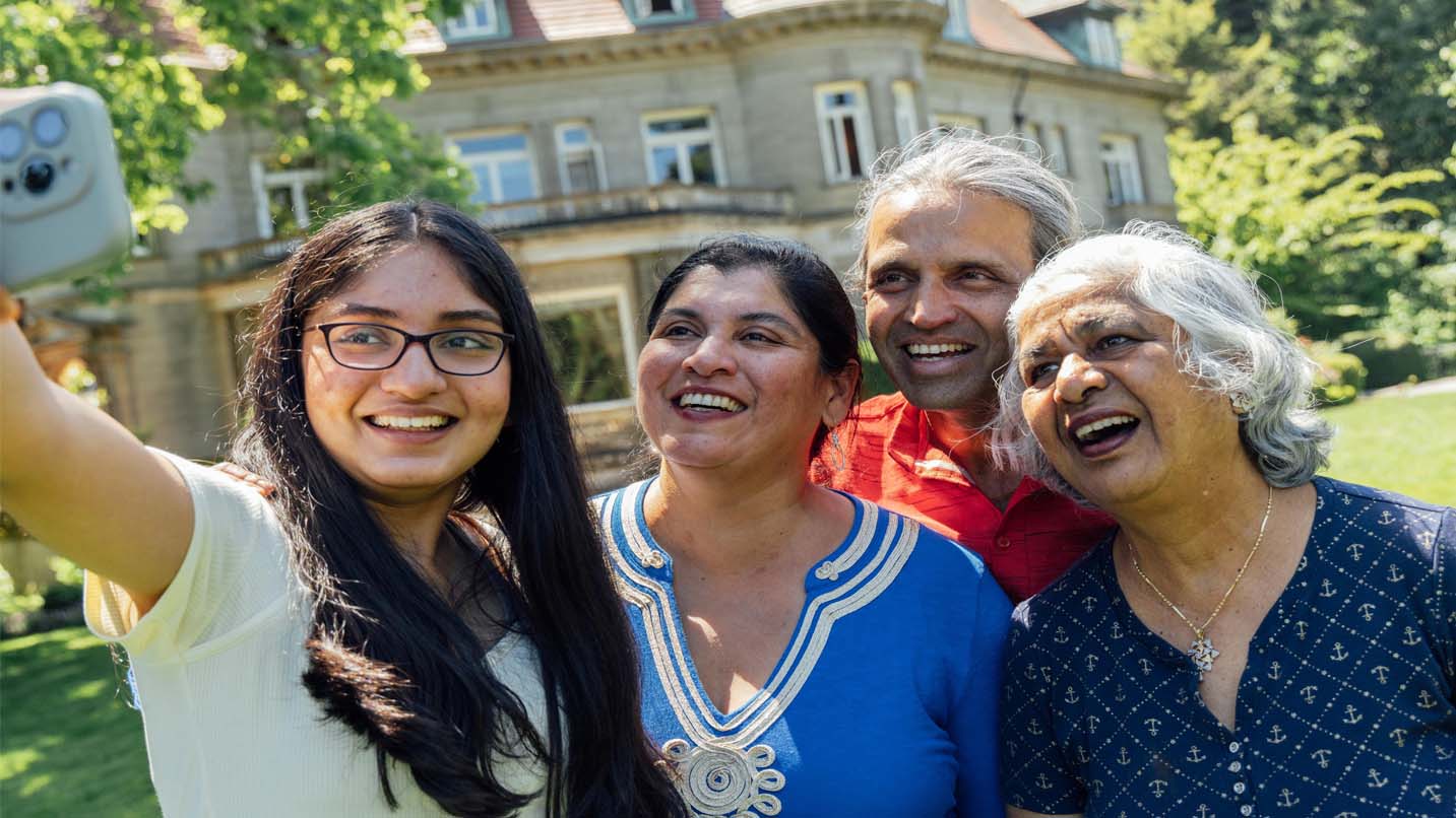 A South Asian family takes a selfie ouside the historic Pittock Mansion.