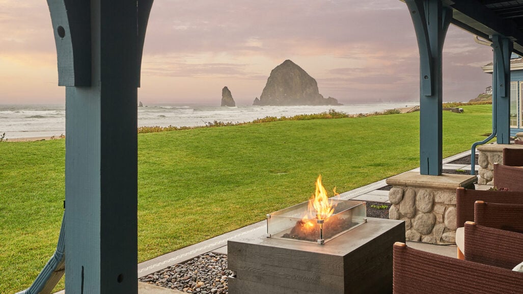A covered porch with a fire pit overlooking the beach and Haystack Rock.