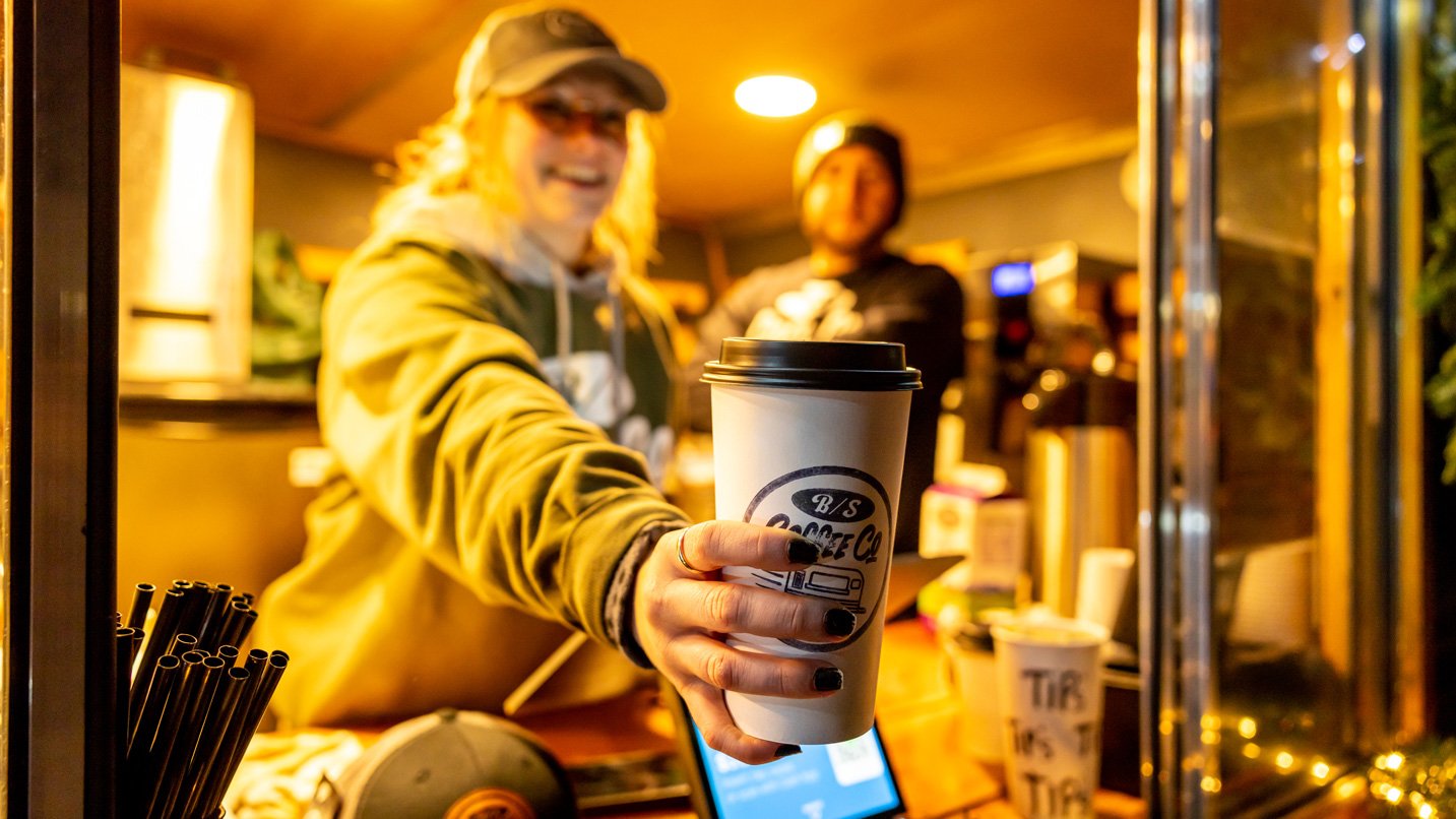 A barista serving a cup of coffee.