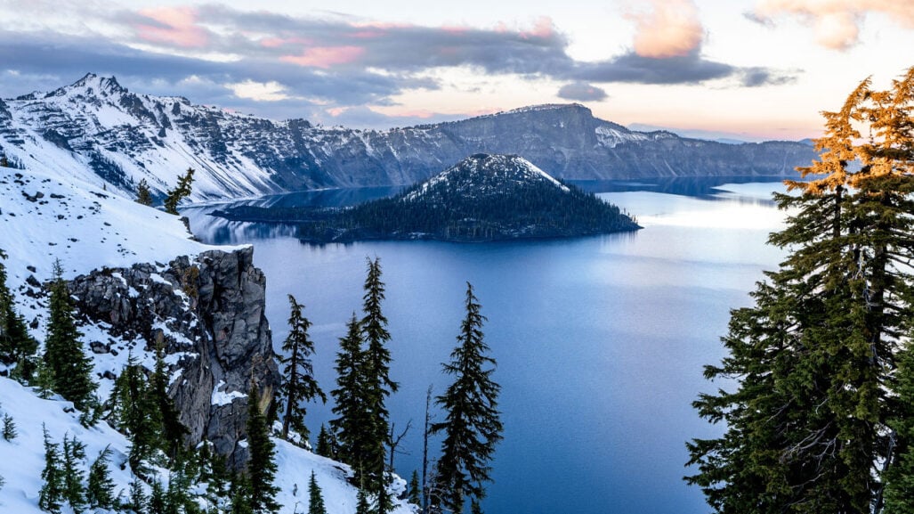 Looking down on a snow-rimmed lake.