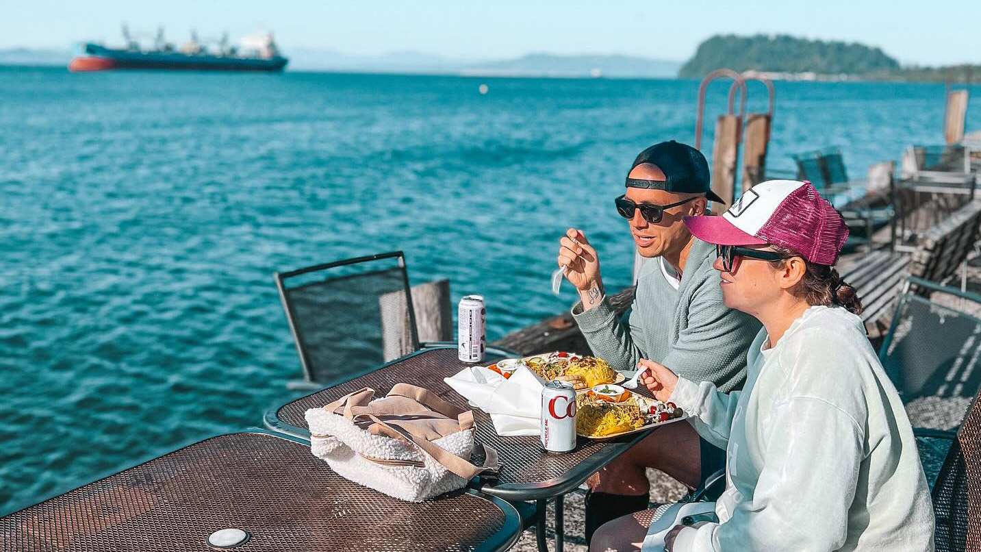 A man and woman eating at an outdoor patio overlooking the Columbia River.