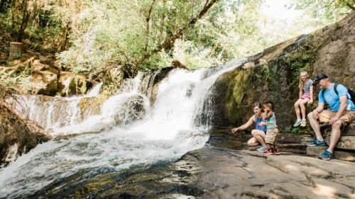 A family with a young child and toddler near a waterfall.