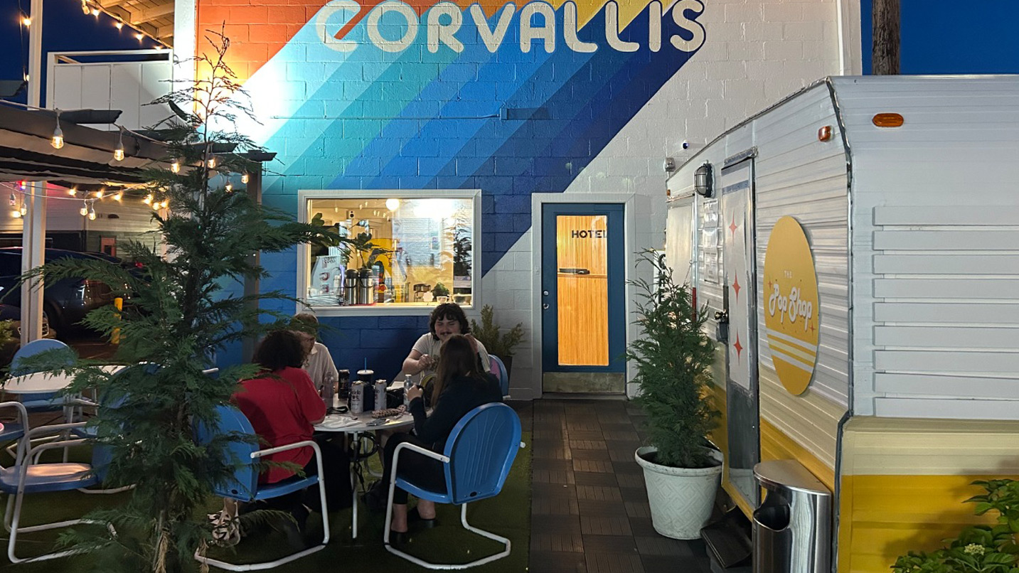 A group of people sit and drink at a table at an outdoor hotel patio.
