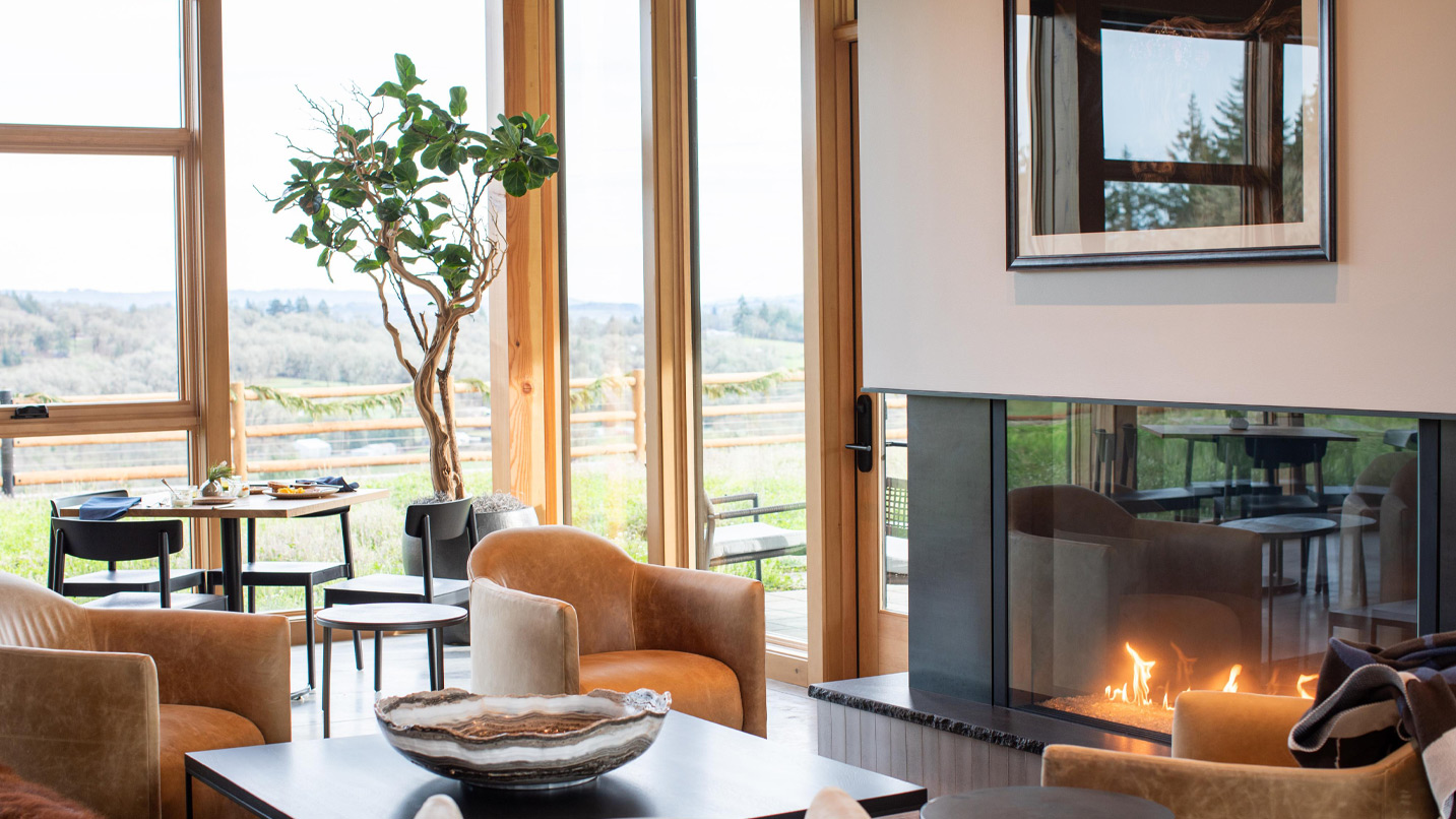 A room with chairs around a modern fireplace.