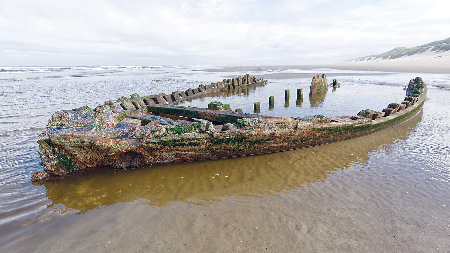 A wooden ship hull on a beach.