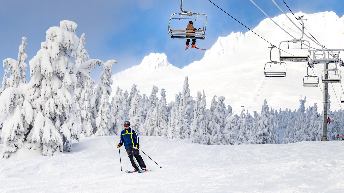 A person skis down a mountain underneath a chairlift.