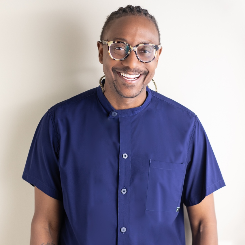 Man wearing blue shirt and glasses smiles at camera