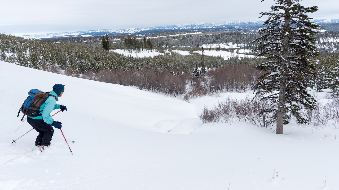 A person downhill skiing on a snowy mountain.
