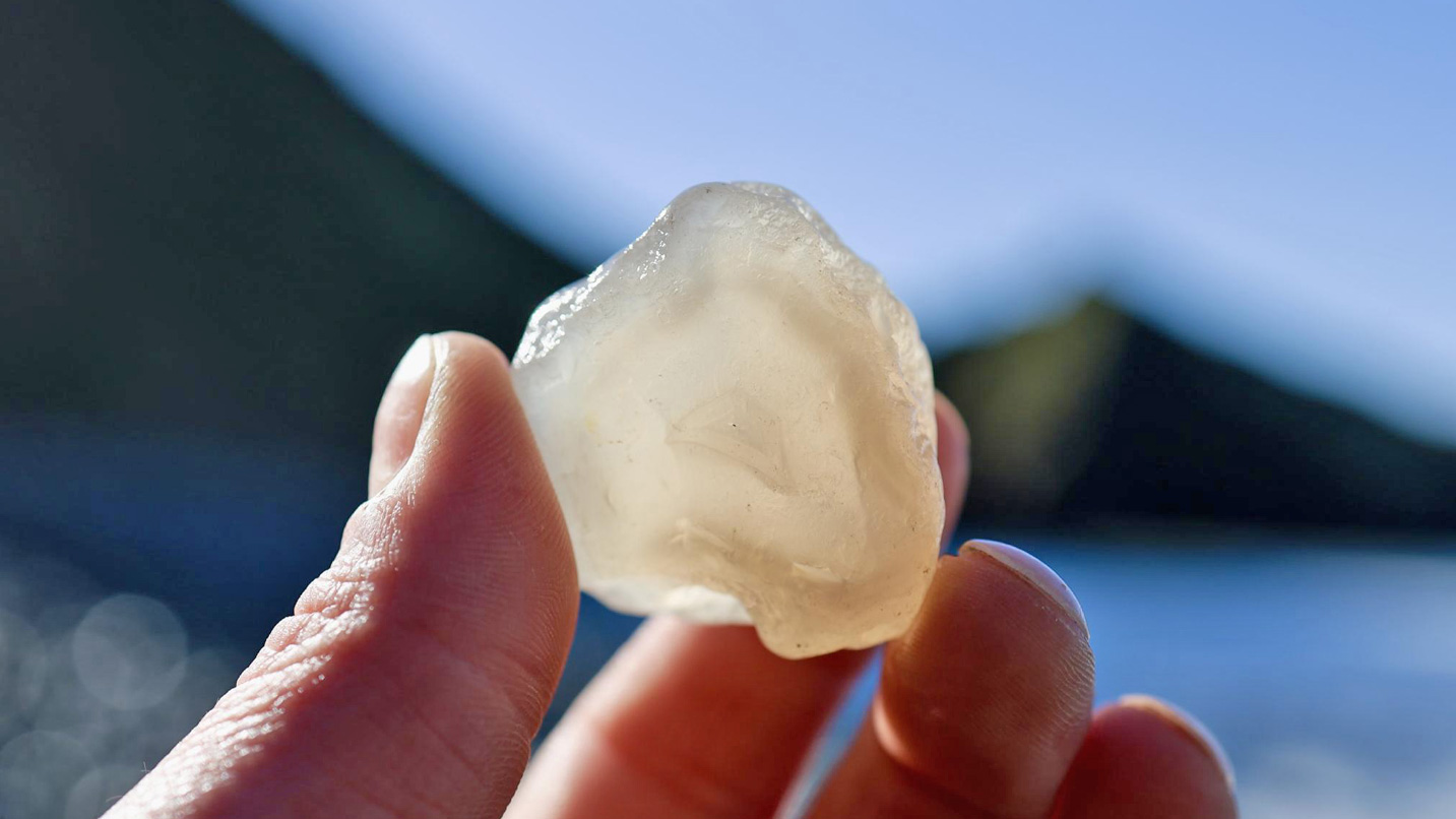 A hand holding a translucent white rock.