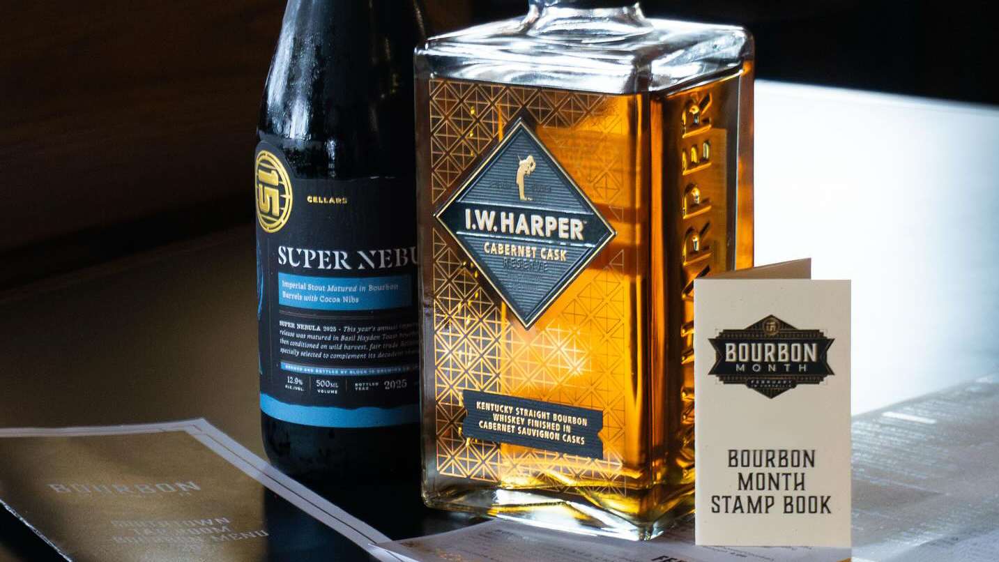 Closeup of a bottles of bourbon and a "Bourbon Month" stamp booklet.