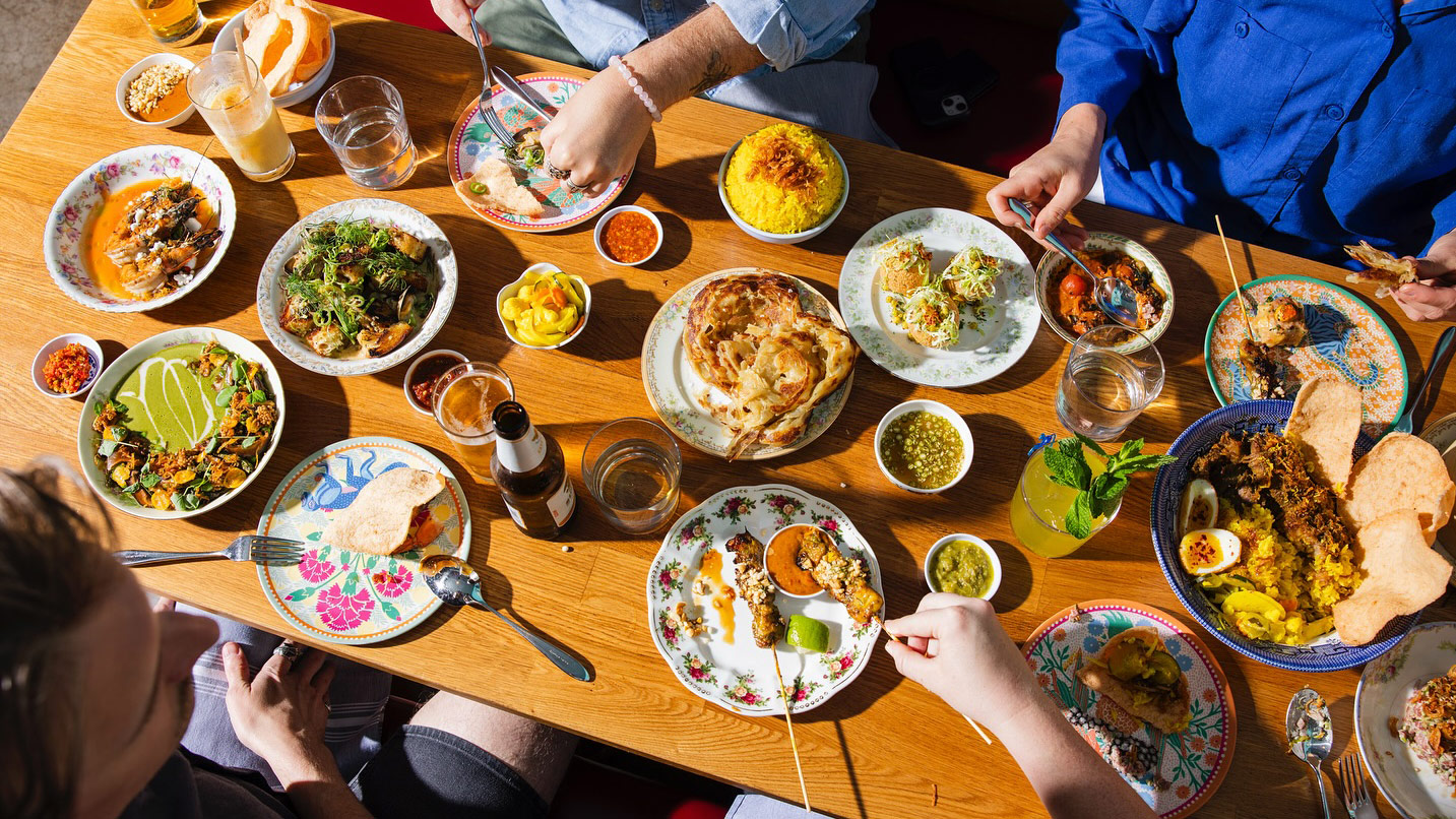 Top down view of a table full of Indonesian-inspired dishes and drinks.