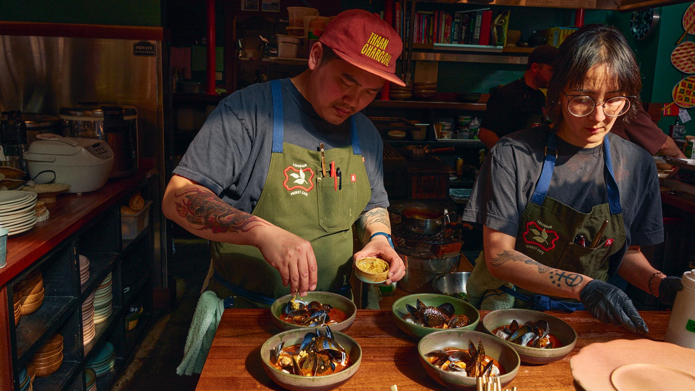 Two workers plating the final touches on clam dishes.
