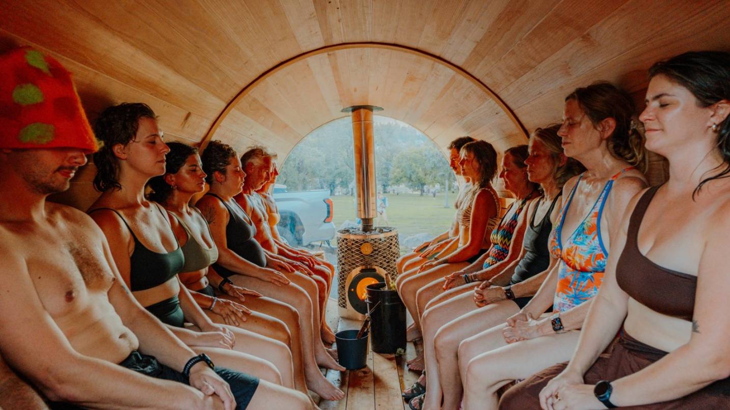 Several people inside a small, mobile sauna.