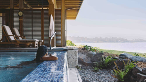 A woman at the edge of a ground-floor pool overlooking the view of the coast.