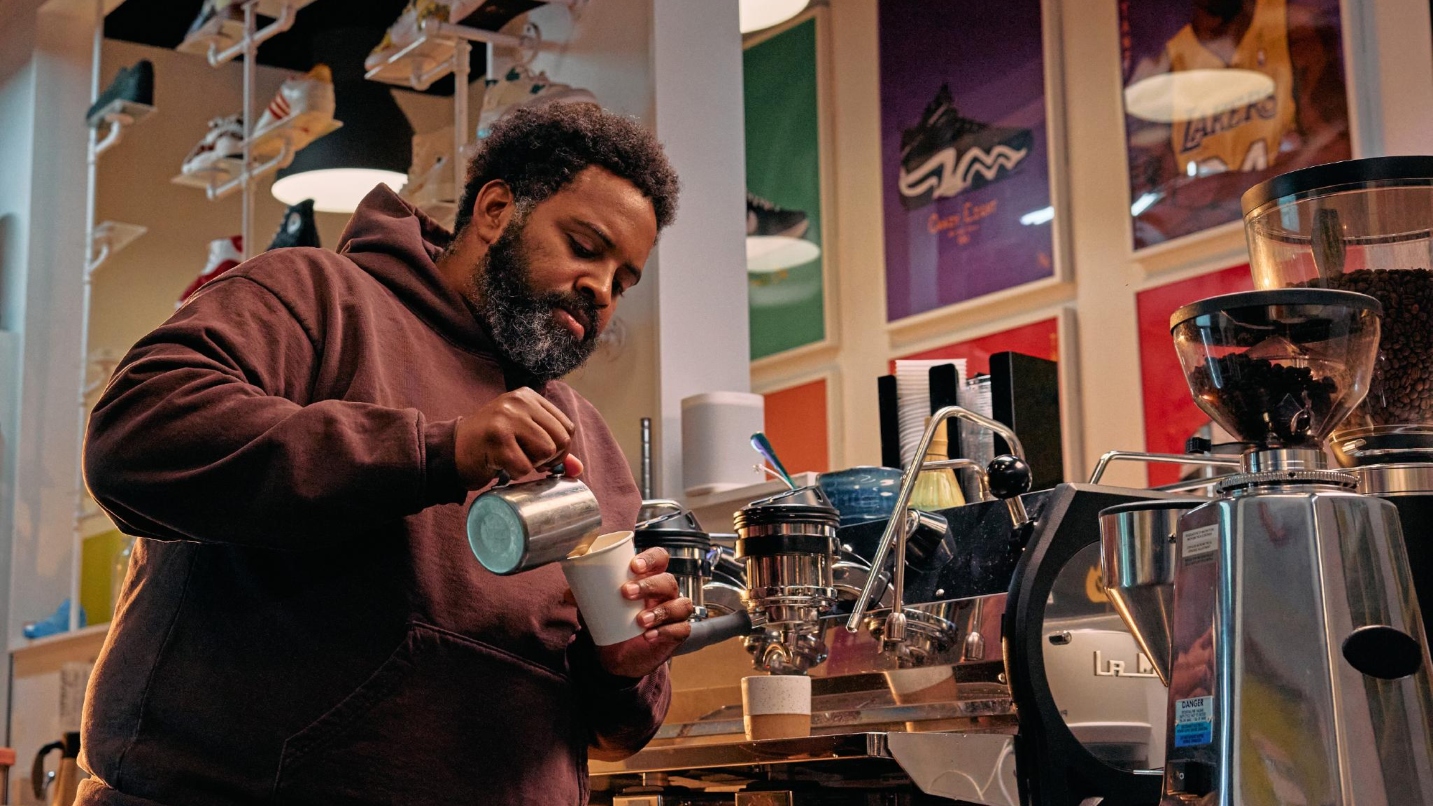 Man pours coffee into cup with colorful background