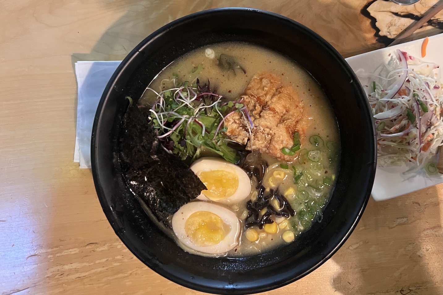 An overhead view of a bowl of ramen with egg, seaweed, and chicken.