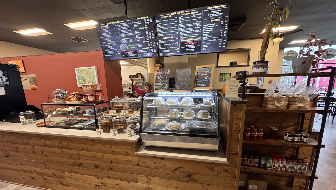 The counter at River Daze showing the menu and a selection of pastries and a cold case.