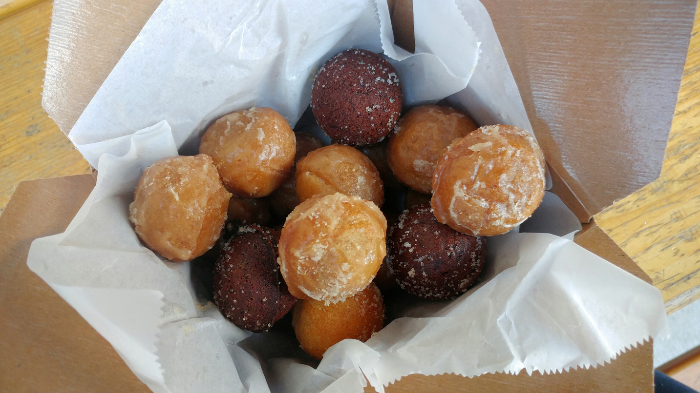 A box full of plain and chocolate donut holes.