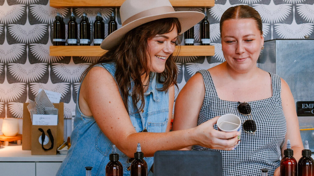 Two people behind a counter holding a cup.
