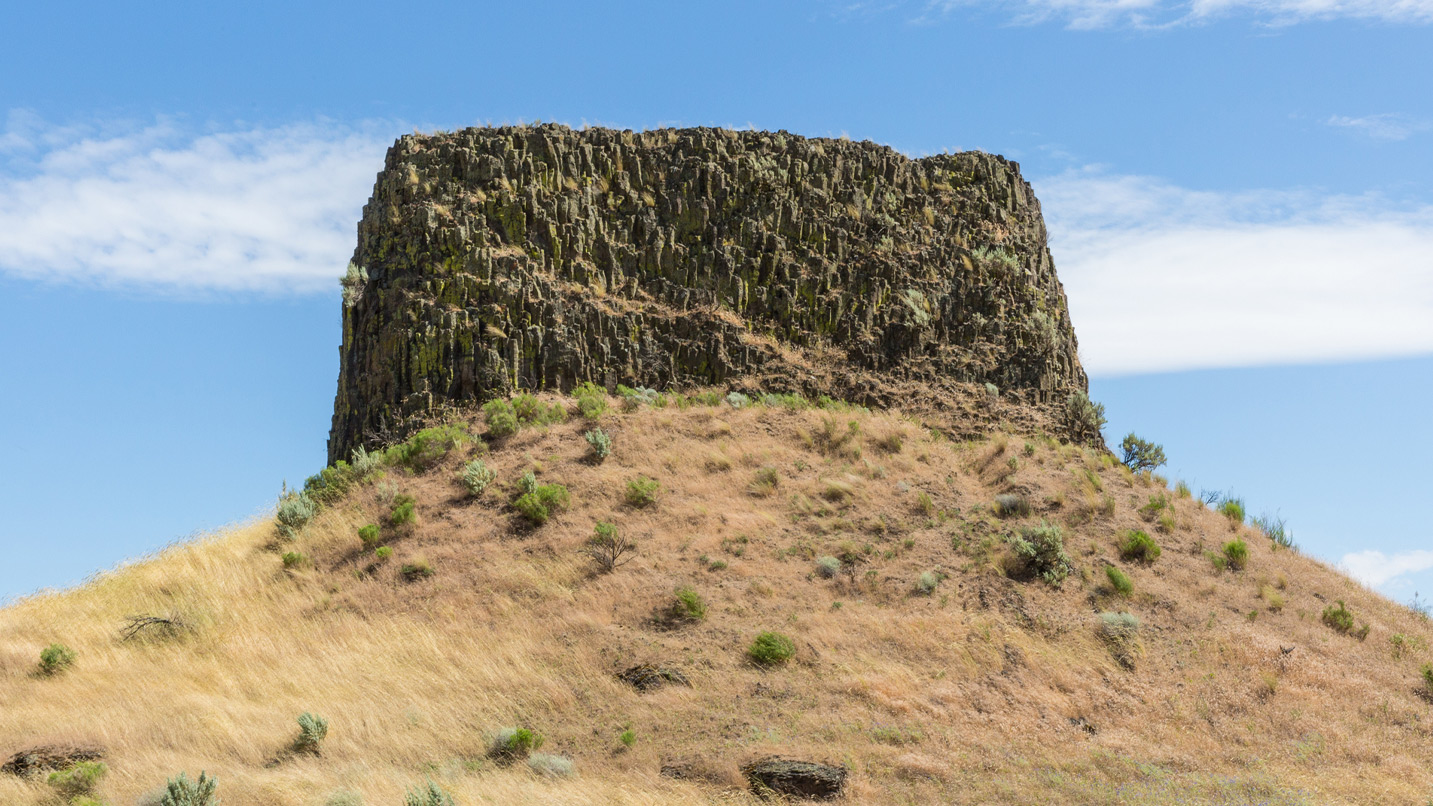 A large rock formation jutting out of a hill.