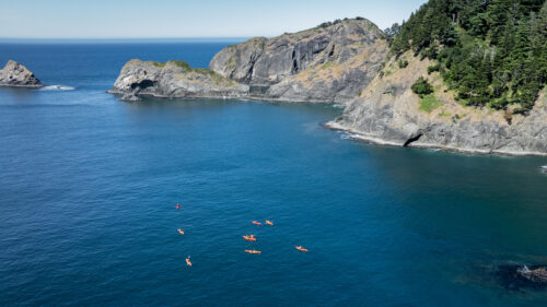 An aerial view of kayakers in a protected ocean cove.