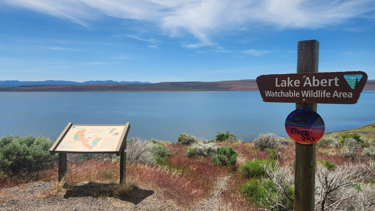 An interpretive sign in front of a lake.