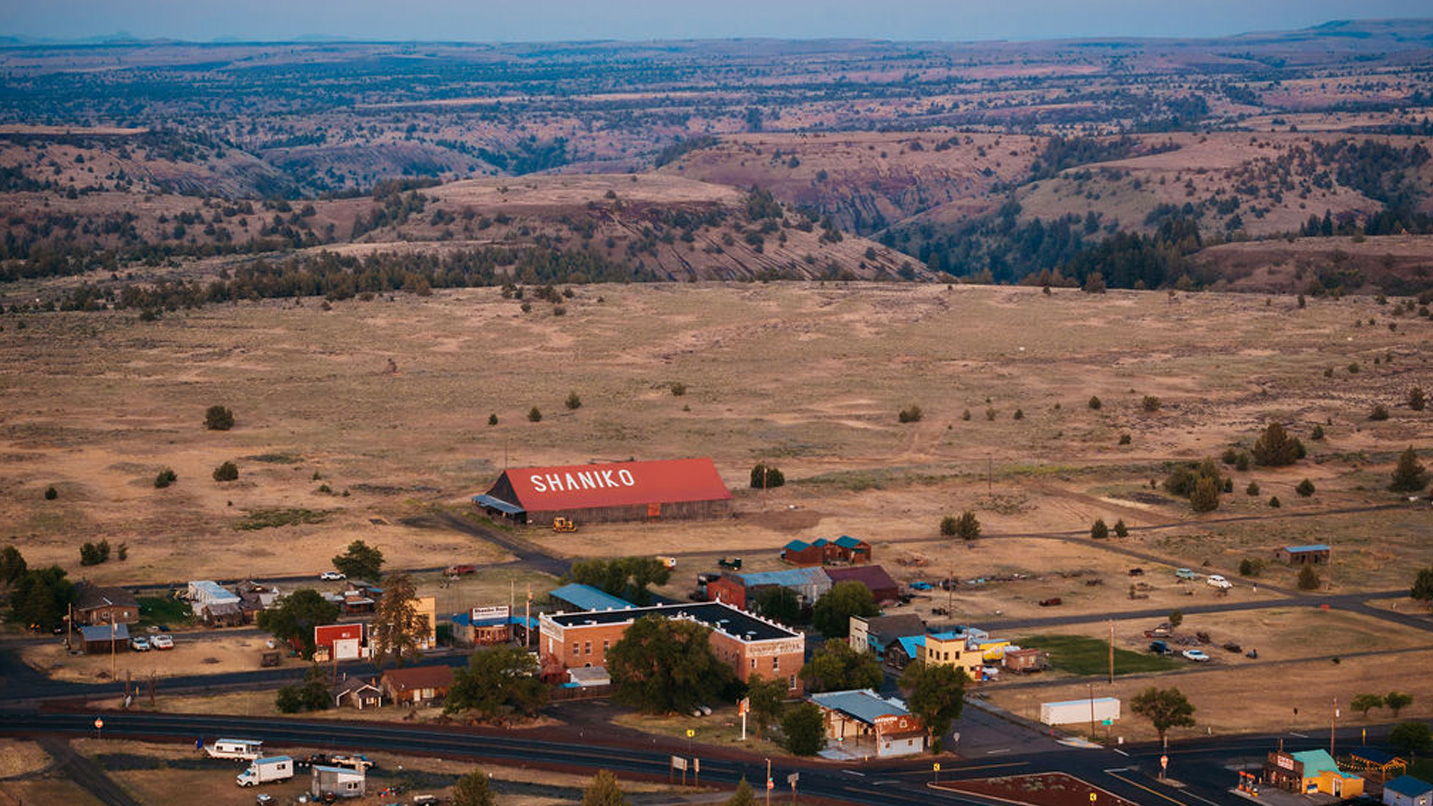 An aerial view of a small town with the word Shaniko painted on top of a barn's roof.