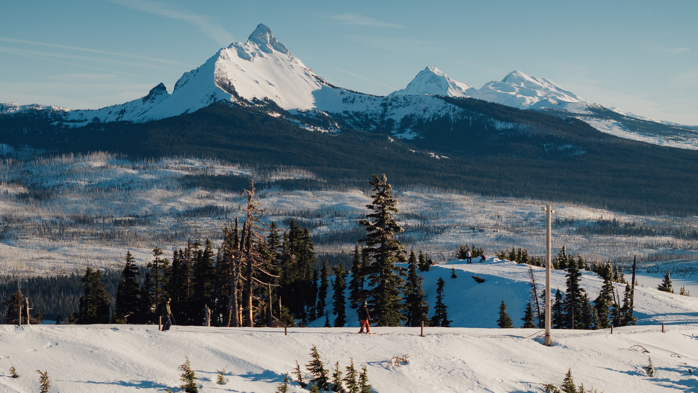 People skiing with snow-capped mountains in the distance.