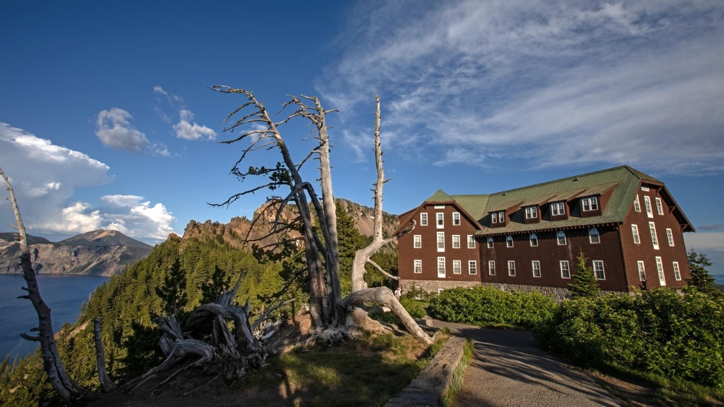 Large lodge building next to a caldera lake, trees and blue sky