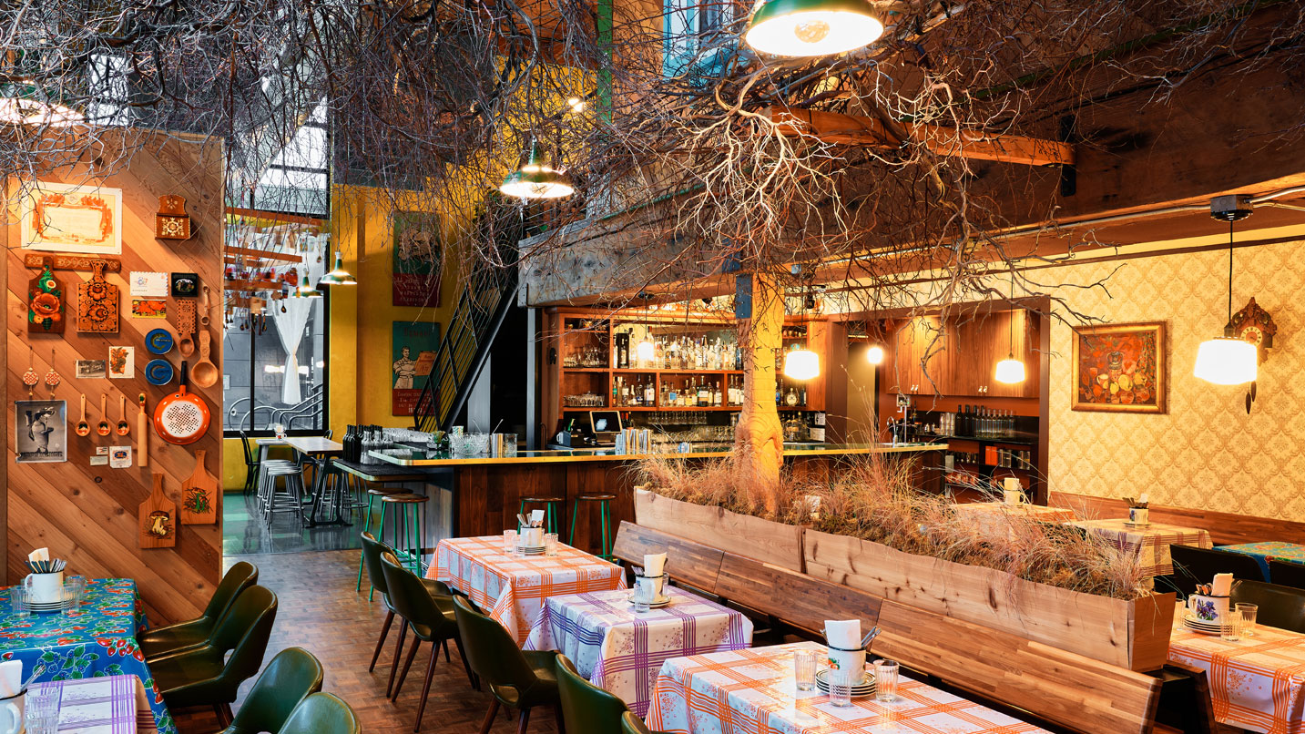 Interior of restaurant space, including several tables and a large bar area, in a homestyle decor.