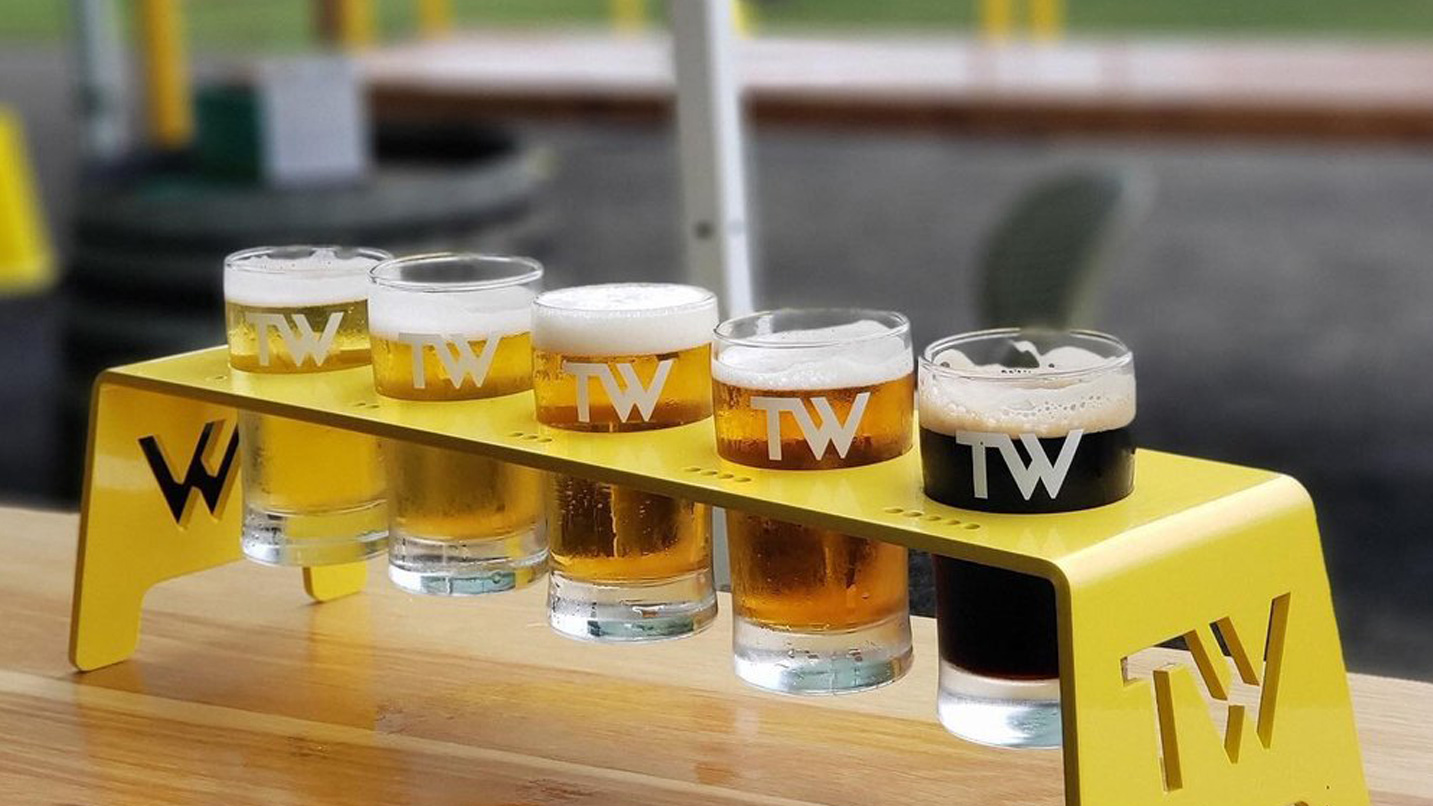 A flight of beers, ranging in light to darker color. Each glass is stamped with "TW."