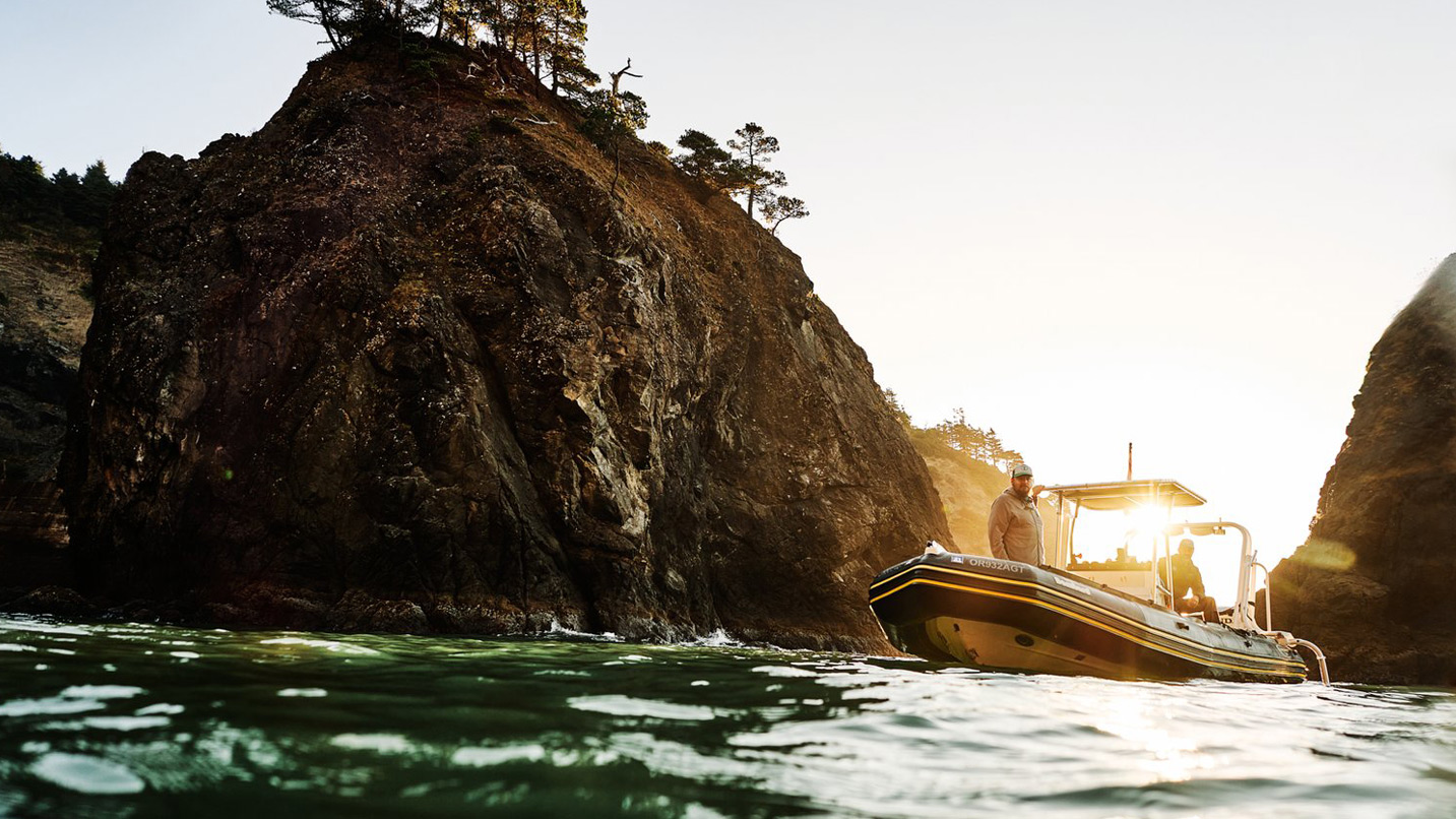 A boat maneuvers into a tight cove surrounded by sea stacks.