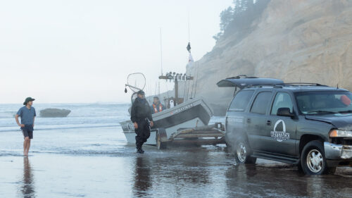 People unload a boat onto the beach.