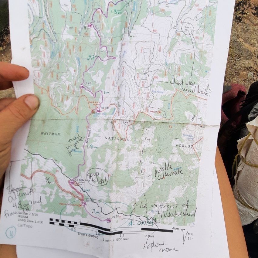closeup of trail map with handwriting and someone's hand on the left holding it
