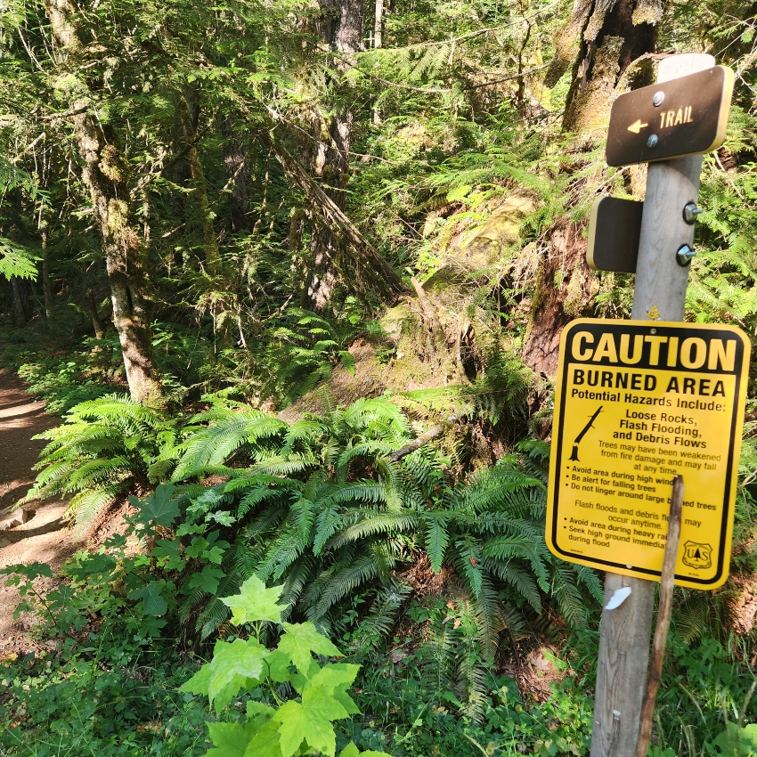 Yellow "caution" sign includes alerts for burn areas on the trail