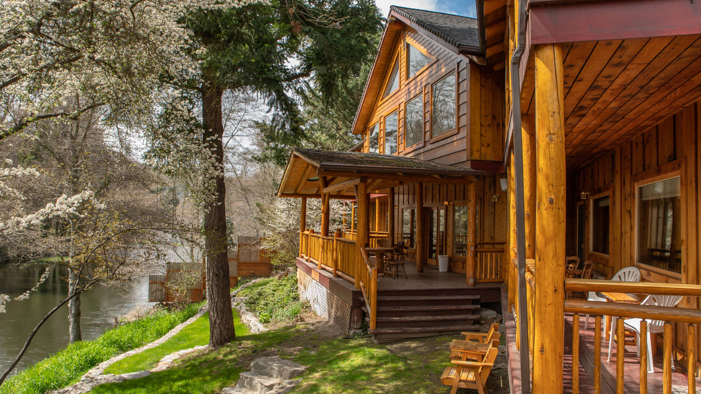 A wooden lodge cabin on the banks of a river.
