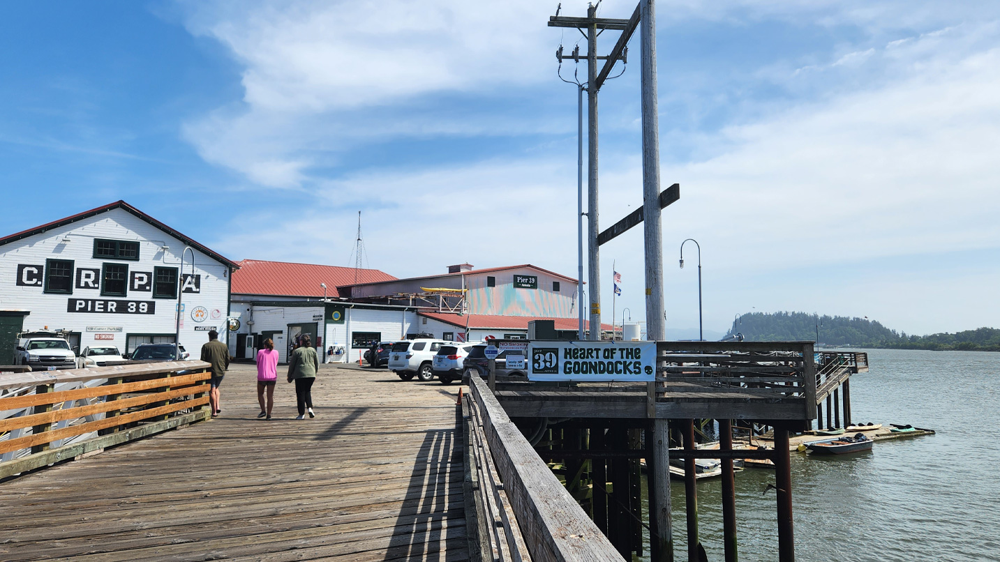 Two people walk towards a building at the end of Pier 39 in Astoria.