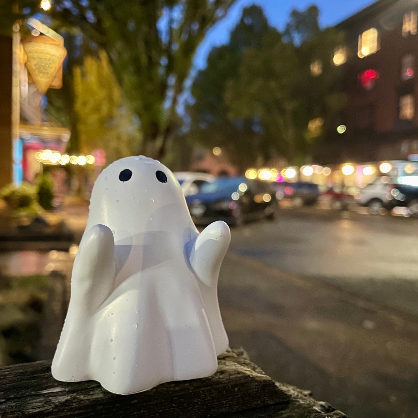 Toy ghost against a background of blurred city main street lights in the evening