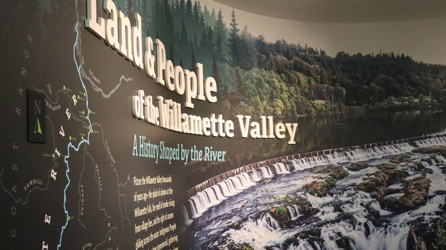 A wall mural with a large photo of a dammed river, with large lettering that reads "Land and people of the Willamette Valley" with more contextual text.