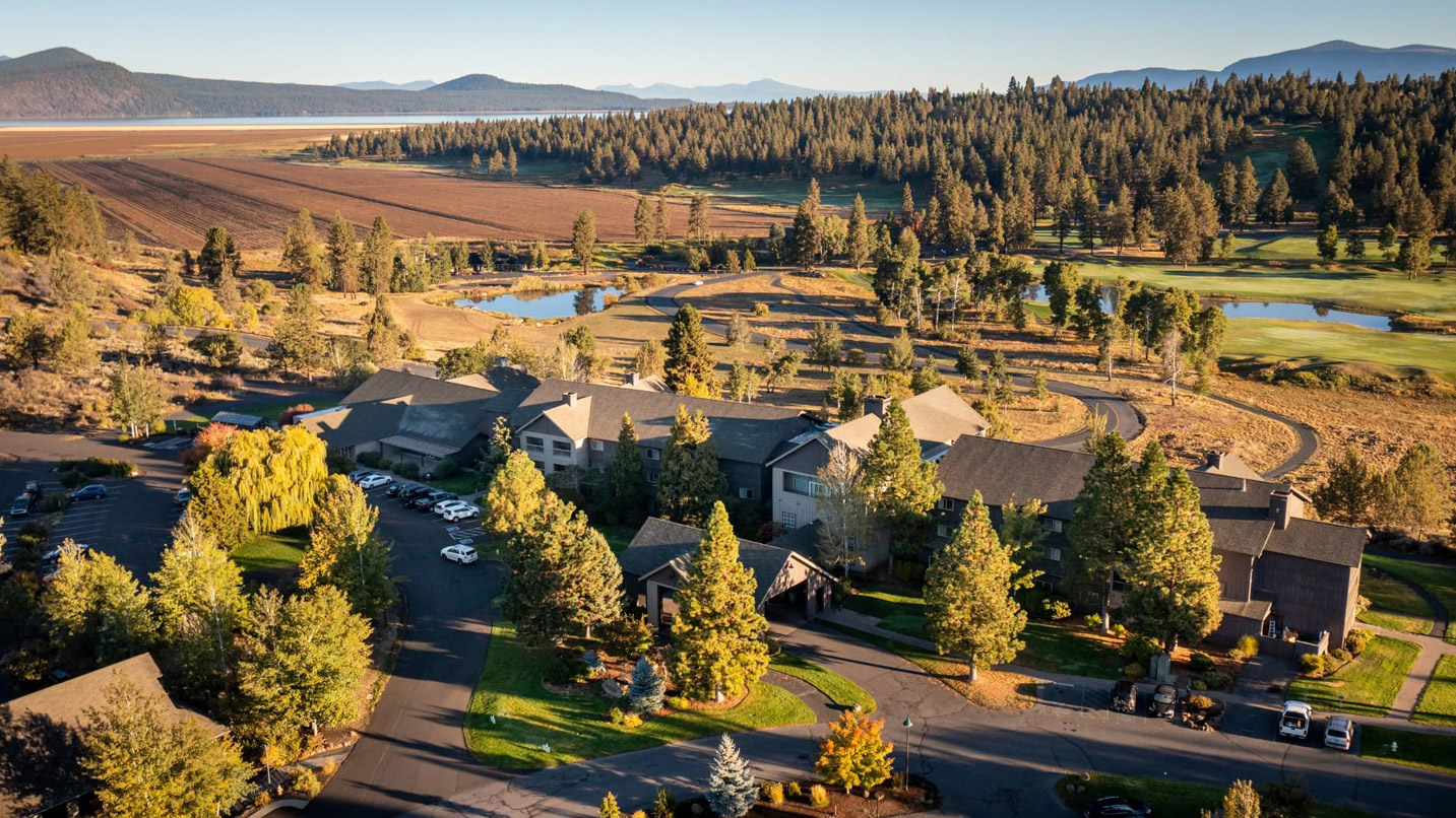 Aerial view of a large resort building and it's surrounding landscape, including large ponds, evergreens and the Klamath River in the distance.